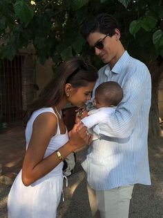 a man and woman holding a baby in their arms