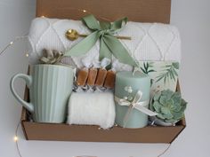 a gift box with candles, mugs and blankets