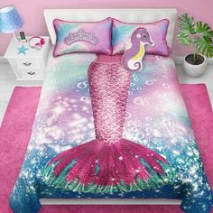 a bed with a pink and blue comforter next to a potted palm tree