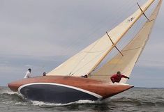 a sailboat with two men on the front and side of it in the water