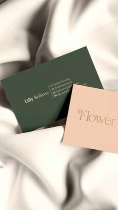 two business cards sitting on top of a white satin bed sheet with the words, lily bellrose