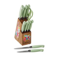 the green knifes are sitting on top of the wooden block with floral designs and black handles