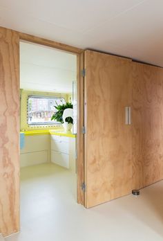 an open door leading to a kitchen with yellow counter tops and white flooring on the walls