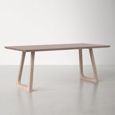 a wooden table sitting on top of a white floor next to an empty wall with no one around it