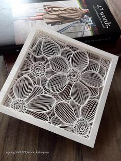 a book sitting on top of a wooden table next to a cut out paper flower