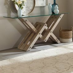 a glass table with wooden legs and a mirror on the wall in front of it