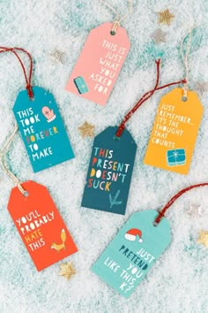 six colorful tags with different sayings hanging from string on snow covered ground next to confetti cones