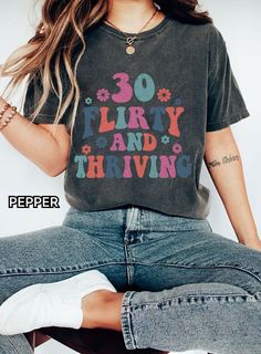 "The model is wearing the color Charcoal.  Celebrate hitting the big 3-0 in style with this cheeky \"30 Flirty & Thriving\" tee! 🎉 The perfect 30th birthday gift for the fabulous woman embracing this milestone year. This retro-inspired tee features distressed text designed in a vintage cursive font. The light pink color adds to the feminine, flirty vibe. 💕 Crafted from 6.0 oz 100% cotton, this tee has a slim feminine fit that flatters curves. Pair with jeans or style it tucked into a skirt for that \"30 and thriving\" look! 👗 Great 30th birthday gift idea for yourself or that fun friend ready to take on their 30s in fearless, flirty fashion. 🥳 This tee is made right here in the USA and machine washable for easy care. It comes in women's sizes S-5XL so all can rock their 30s in style! L Teachers Halloween, Look Retro, Dance Mom, Color Images, Teacher Tees, Art Technology, Comfort Colors Tee, Retro Halloween, Teacher Tshirts