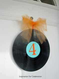 a vinyl record hanging on a door with an orange bow and number four painted on it