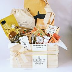 a wooden box filled with lots of different types of food and snacks on top of a white table