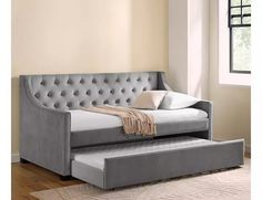 a gray daybed with a pull out trundle and pillows on it in front of a window