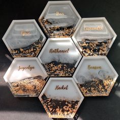 six hexagonal dishes with gold and black food in them that have names on them