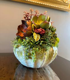 a glass bowl filled with lots of different types of flowers on top of a table