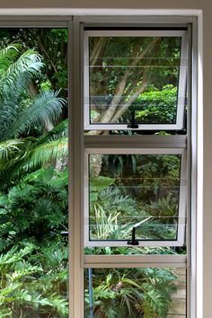 an open window with plants and trees in the background