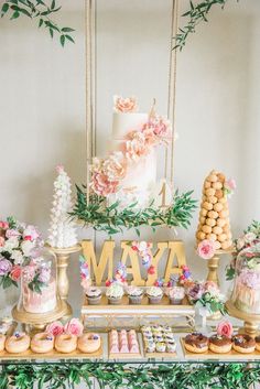 the dessert table is decorated with flowers and macaroons