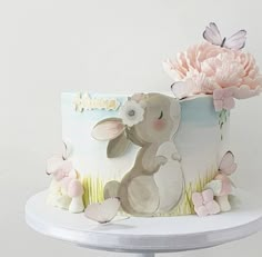 there is a cake decorated with flowers and a bunny on the top one has a pink flower in it