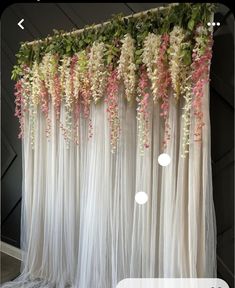 flowers are hanging from the side of a white drape with pink and green foliage