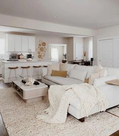 a living room filled with white furniture and lots of pillows on top of a rug