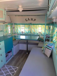 the inside of a camper with blue and green decor on the walls, couches, table and windows