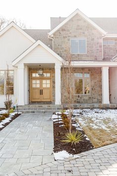 a house with a large front door and brick walkway leading to the front entrance in winter