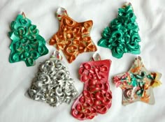 five christmas ornaments are sitting on a white sheet and one is green, red, orange, and silver