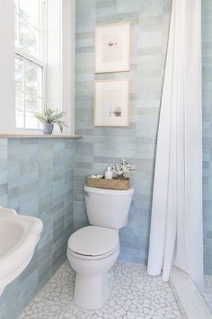 a white toilet sitting in a bathroom next to a sink and shower stall with blue tiles on the walls