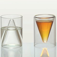 two glasses filled with liquid sitting next to each other