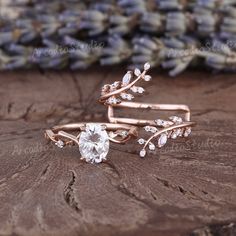 two rose gold wedding rings with white topazte and leaves on the sides, set on a piece of wood