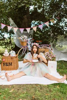 a woman sitting on the ground with her legs crossed and holding a cup in front of her