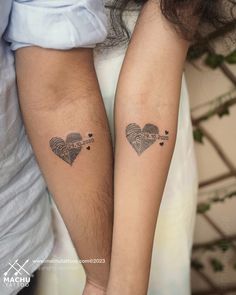 two people holding hands with tattoos on their arms and one has a heart in the middle