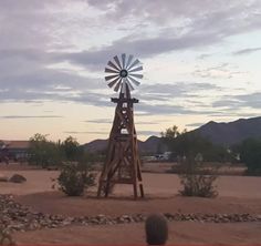 a windmill in the middle of a desert with mountains in the backgrouds