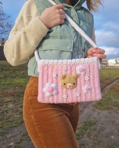 a woman holding a pink purse with a teddy bear on it