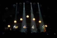 a group of people that are on stage with some lights in the dark behind them