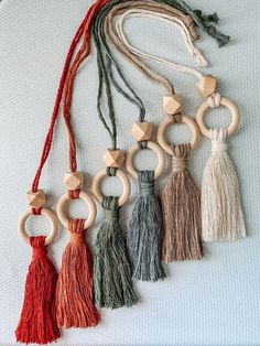 several wooden rings and tassels are arranged on a white surface, one is hanging from a string