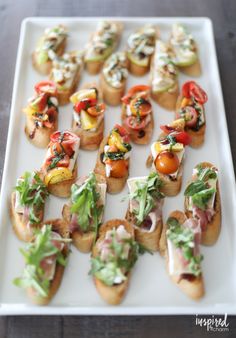 many small appetizers are arranged on a white plate with green garnish