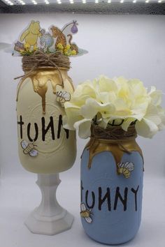 two jars with flowers in them sitting next to each other