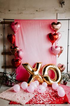 balloons and confetti are scattered on the floor in front of a pink backdrop