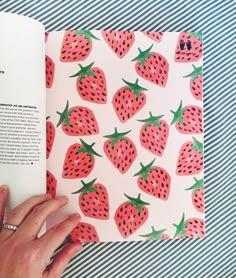 a hand holding an open book with strawberries on it