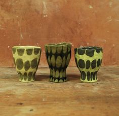 three ceramic cups sitting on top of a wooden table