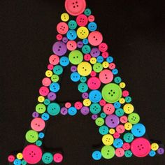 a letter made out of buttons on a black background with the letter a surrounded by many different colored buttons