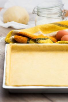 an empty baking pan with eggs and flour on the table next to some other ingredients