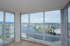 an empty room with large windows overlooking the water and cityscape in the background