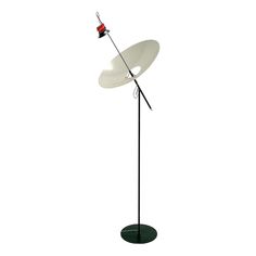 a black and white floor lamp with a red light on it's arm,