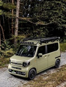 a small van parked in the middle of a wooded area with its roof rack on