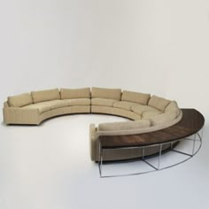 a curved sectional couch sitting on top of a wooden table next to a white wall