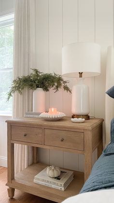 a wooden table topped with a lamp next to a bed