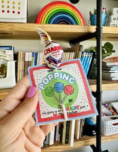 a person holding up a card with the word popping on it in front of a bookshelf