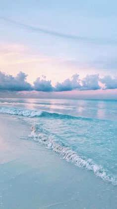 an ocean beach with waves and clouds in the sky