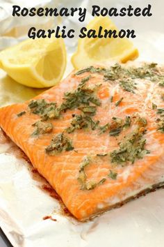 a piece of salmon sitting on top of a piece of foil next to lemon wedges