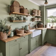 a kitchen filled with lots of green cupboards and shelves next to a white sink